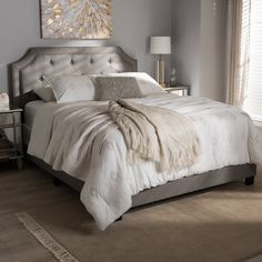 a white bed sitting in a bedroom on top of a wooden floor next to a window