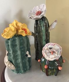 three vases sitting on top of a white table next to each other with flowers in them