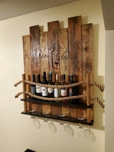 some wine glasses and bottles are hanging on the wall with rope attached to wooden pallets