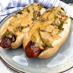 two hot dogs covered in mustard and relish sitting on a plate next to a napkin