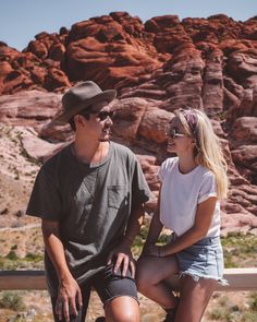 a man and woman sitting next to each other on a wooden bench in the desert