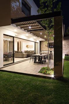 an outdoor living room and dining area are lit up at night