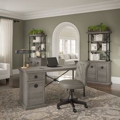 a desk with a laptop on top of it in front of a couch and chair