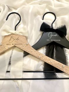 two personalized wooden hangers with black and white bows on them, one for bride and the other for groom