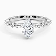 a white gold engagement ring with a pear shaped center stone and side stones on the band