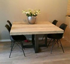 a wooden table with black chairs and a vase filled with flowers on top of it