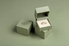 an open box with a ring inside on a gray surface next to it is a diamond in the middle