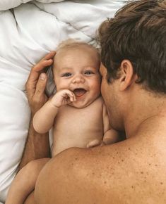 a man laying in bed holding a baby