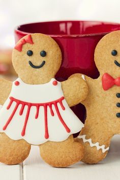 two gingerbread men are standing next to a cup