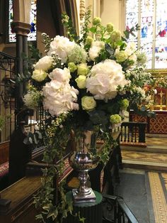 a vase filled with white flowers sitting on top of a wooden table next to a stair case