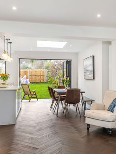 a living room filled with furniture next to a kitchen and an open door leading to a back yard