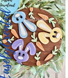 an easter egg decorated with bunny, rabbit and carrots on a wooden plaque surrounded by greenery