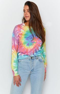 a woman standing in front of a white wall wearing a colorful tie - dyed shirt