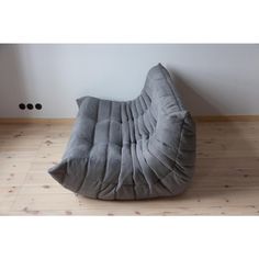 a grey bean bag chair sitting on top of a hard wood floor next to a wall