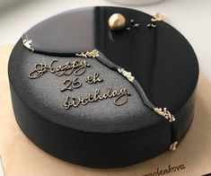 a black cake with gold decorations and writing on it