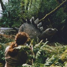 a woman is looking at an animal in the woods with trees and plants around her