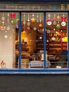 a store front with christmas decorations hanging from the windows and snowflakes in the window