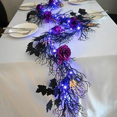 the table is set with white plates and purple flowers