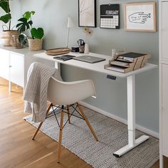 a desk with a chair, lamp and pictures on the wall in front of it