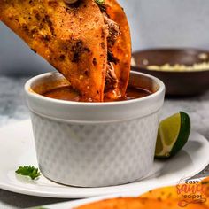 some food in a white bowl on a plate with lime wedges and other foods