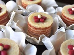 small cupcakes with red and white candies on them are arranged in paper wrappers