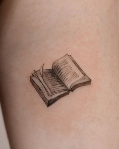 an open book tattoo on the thigh