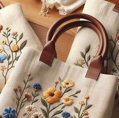 two handbags with flowers on them sitting on a table next to some other items