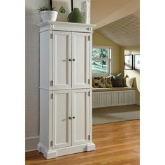 a tall white cabinet sitting on top of a hard wood floor