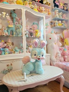 a room filled with lots of stuffed animals on top of a white table and shelves