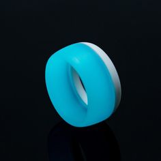 a light blue ring sitting on top of a black surface with its reflection in it