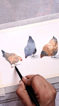 a person is painting three birds with watercolors