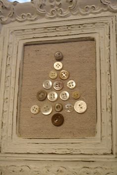 buttons are arranged in the shape of a christmas tree on an old white framed frame