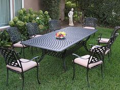 an outdoor table with chairs and fruit on it in the grass near a garden area