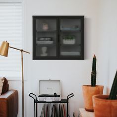 a laptop computer sitting on top of a table next to a lamp and potted plant