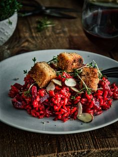 a white plate topped with food next to a glass of wine