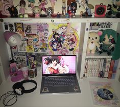 an open laptop computer sitting on top of a white desk covered in anime figurines