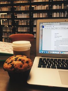 a laptop computer sitting next to a muffin