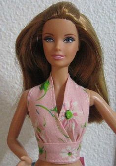 a barbie doll is wearing a pink top and blue pants with green flowers on it