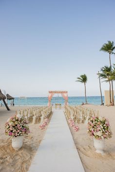 an outdoor ceremony set up on the beach with chairs and flowers in vases at the end