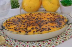 a dish filled with pudding sitting on top of a table next to two lemons