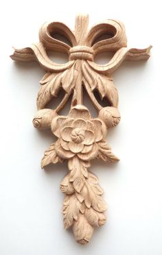 a wooden cross with flowers and leaves carved into it's sides on a white surface