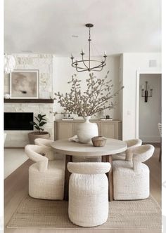 a dining room table with four chairs and a vase on top of it in front of a fireplace