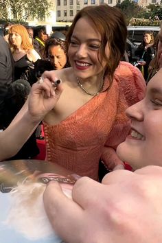 a woman in an orange dress smiles as she is surrounded by other people