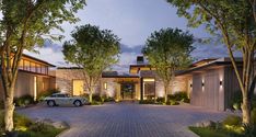 a car is parked in front of a large house at night with trees and bushes