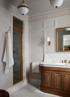 a bathroom with marble counter tops and wooden cabinetry, along with white towels hanging on the wall