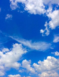 an airplane is flying through the blue sky with clouds in the background