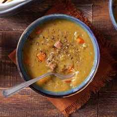 two bowls filled with soup on top of a wooden table next to breadsticks