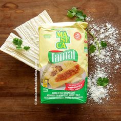 a bag of tamal sitting on top of a wooden table next to napkins