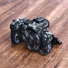 a camo camera sitting on top of a wooden table next to a black object