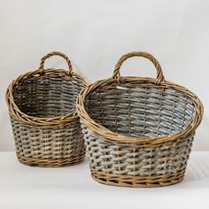 two wicker baskets sitting side by side on a white surface with one empty basket in the middle